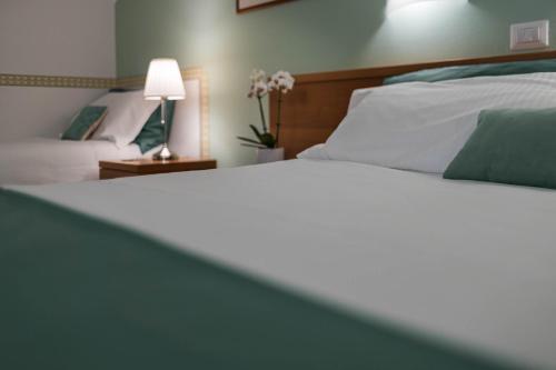 a bedroom with a white bed with a lamp and flowers at Hotel Roma in Palmanova
