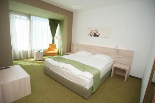 a bedroom with a large bed and a chair at Hotel Armatti in Braşov