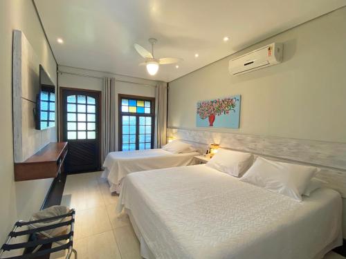 two beds in a bedroom with two windows at Porto Pacuíba Hotel in Ilhabela