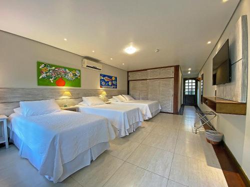 a hotel room with two beds and a flat screen tv at Porto Pacuíba Hotel in Ilhabela