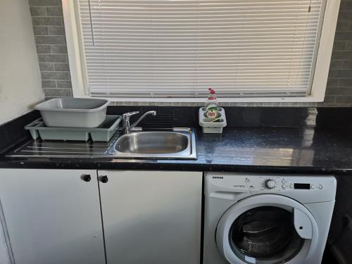 a kitchen counter with a sink and a washing machine at Modern property close to Aintree Hospital & Motorways in West Derby