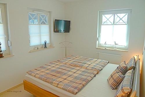 a bed in a bedroom with two windows and a tv at Kapitän ParowBrigantine in Zingst