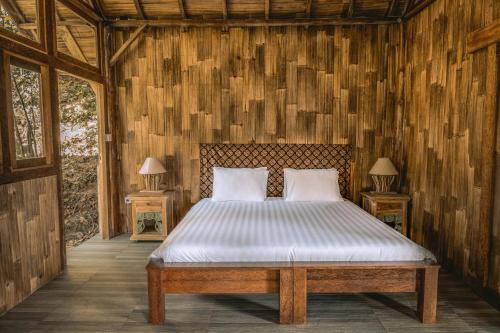 a bedroom with a bed in a wooden wall at Gumi Ayu EcoStay in Munduk