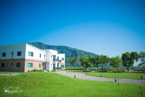 un grand bâtiment blanc sur une colline avec une pelouse dans l'établissement Simple Life, à Yuli