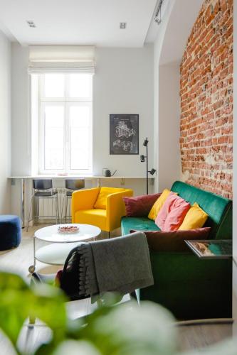 a living room with a green couch and a brick wall at Elegant 2BR, Amazing Old Town Views, Plac Solny Walk to Rynek! Amenities in Wrocław