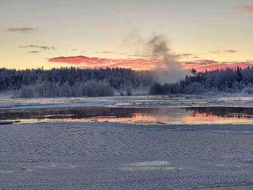a steamboat in the middle of a frozen river at sunset at Lagomhuset - A peaceful holiday in Swedish Lapland in Vidsel