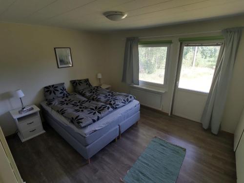 1 dormitorio con 1 cama y 2 ventanas en Lagomhuset - A peaceful holiday in Swedish Lapland en Vidsel