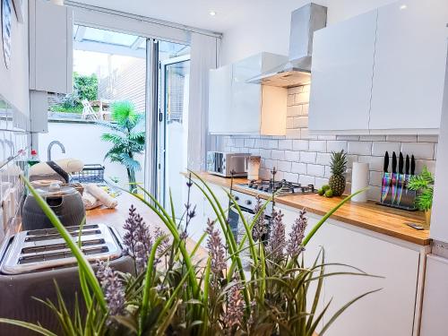 a kitchen with white cabinets and some plants in it at 4bd Hidden gem by Brighton Station in Brighton & Hove