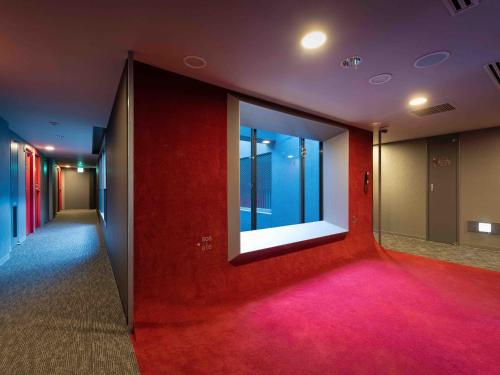 a hallway with a red wall and a large window at EN HOTEL Hiroshima in Hiroshima