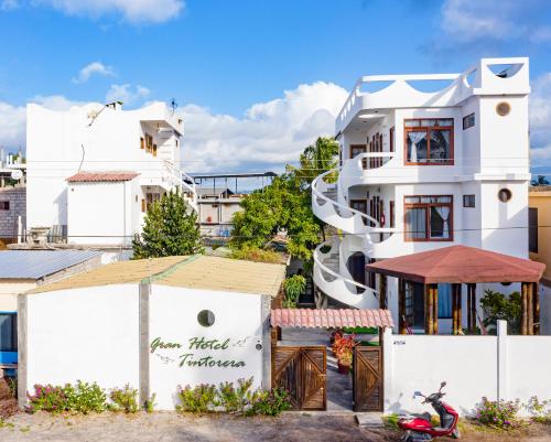 una casa blanca con una moto delante de ella en Gran Hostal Tintorera en Puerto Villamil