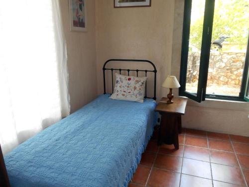 a bedroom with a bed with a blue comforter and a window at Polytropon Studio ground floor in Kefallonia