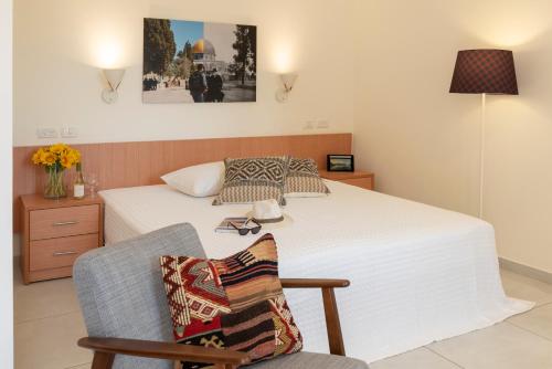 a bedroom with a bed and a chair with a pillow at Austrian Pilgrim Hospice in Jerusalem