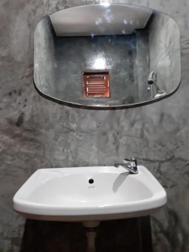 a white sink in a bathroom with a mirror at เฮือนไม้ชมนาด Huanmaichommanard in Chiang Mai