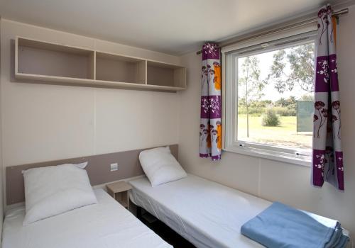 two beds in a room with a window at Camping Miami plage in Poggio-Mezzana