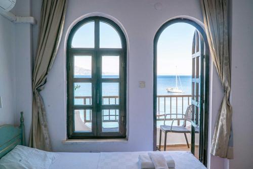 a bedroom with two windows and a bed and a balcony at The Diplomat Hotel in Turunç