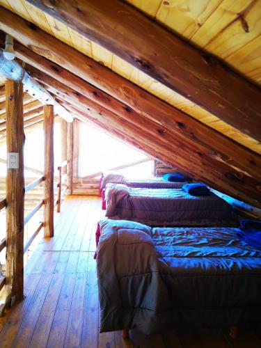two beds in a cabin with a wooden ceiling at Cabañas NAOL in Uspallata