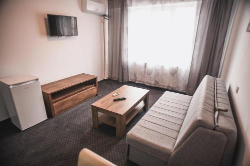 a living room with a couch and a coffee table at Petrosani Camere de Inchiriat - Hotel Petroshani srl in Petroşani