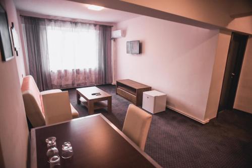 a room with a table and chairs and a window at Petrosani Camere de Inchiriat - Hotel Petroshani srl in Petroşani
