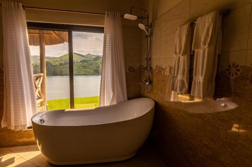 a bath tub in a bathroom with a window at Crater Safari Lodge in Kibale Forest National Park