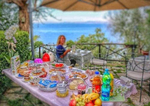 a table with food and drinks on it with a woman at La Palombara B&B in Vico Equense