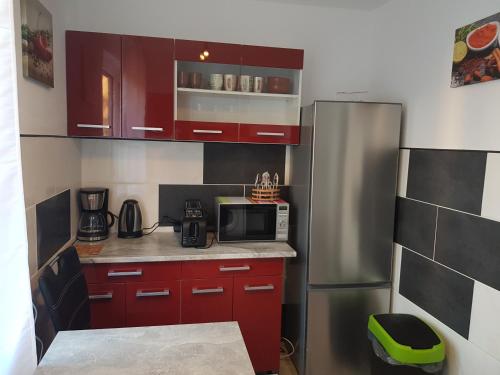 a small kitchen with red cabinets and a stainless steel refrigerator at Duisburg Beeck in Duisburg