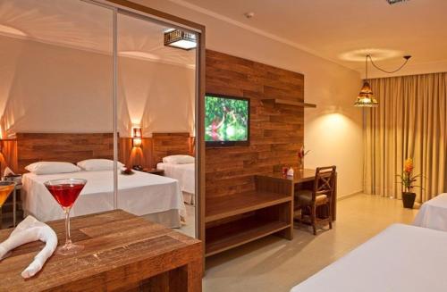 a hotel room with two beds and a wine glass on a table at Resort da Ilha in Sales