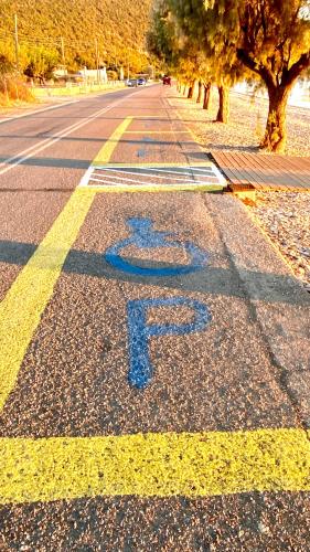 a street with a blue letter f on the road at Blumenhaus (Spiti Louloudia) in Paralía Sergoúlas