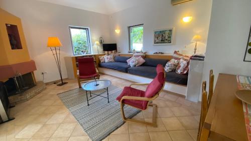 uma sala de estar com um sofá azul e cadeiras vermelhas em Blumenhaus (Spiti Louloudia) em Paralía Sergoúlas
