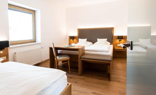 a room with a bed and a desk and a bed and a desk at Hotel Gasthof Rosenwirt in Au in der Hallertau