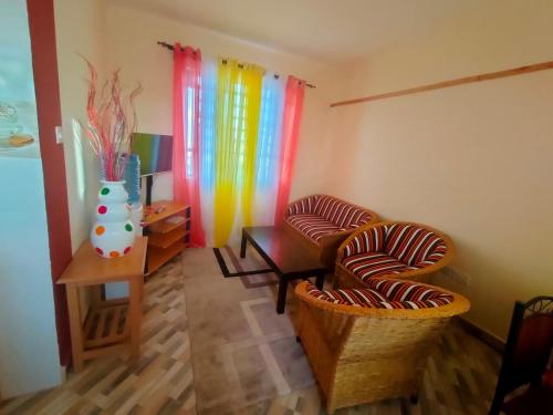 a room with two chairs and a table with colorful curtains at Amber Apartments G2 Kitengela in Athi River