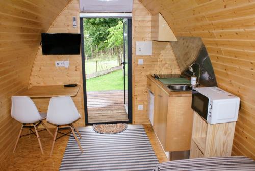 a kitchen in a tiny house with a sink and two chairs at Casa Matilde - Alombada Family Lodge in Águeda