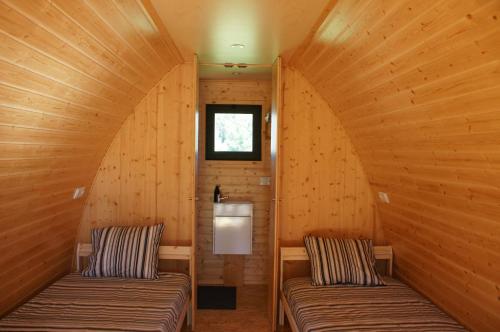 twee bedden in een kamer met houten wanden en een raam bij Casa Matilde - Alombada Family Lodge in Águeda