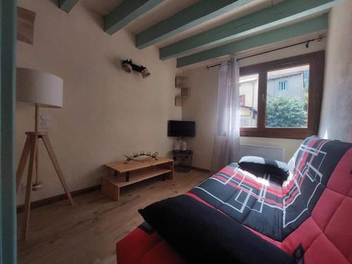- un salon avec un canapé rouge et une fenêtre dans l'établissement Petite maison de vacances en Cévennes, à Florac Trois Riviere