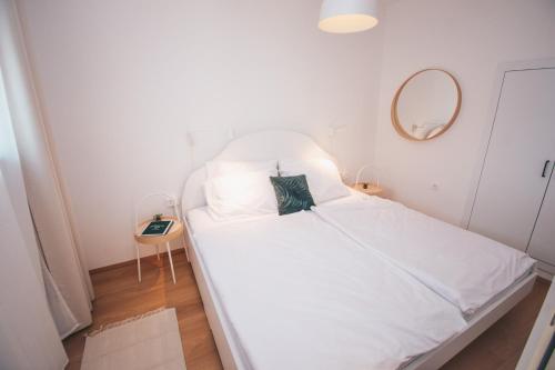 a white bed in a small room with a mirror at NA Apartments in Maribor
