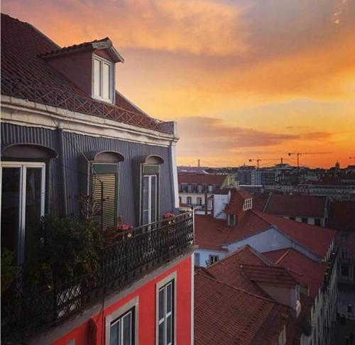 a building with a balcony with a sunset in the background at SoQuiet in Lisbon