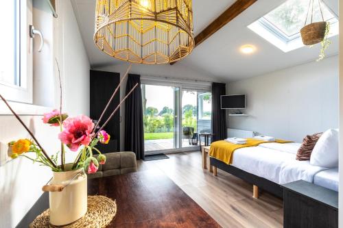 een slaapkamer met een bed en een vaas met bloemen bij Grenzeloos in Doldersum
