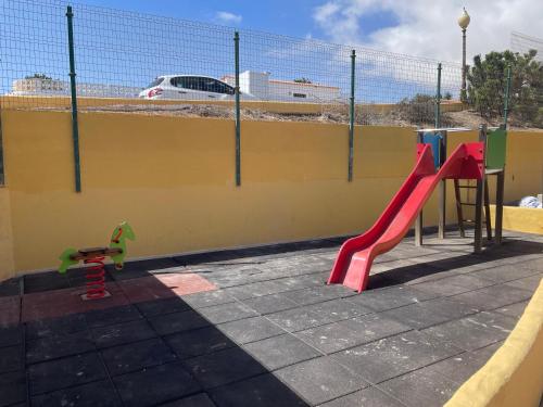 einen Spielplatz mit einer roten Rutsche und einer Spielstruktur in der Unterkunft Casa Ozzy in Costa Calma