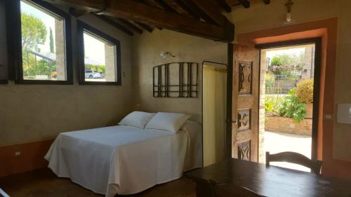 a bedroom with a bed and a table and a window at MYRTUS PODERE CUNINA in Buonconvento