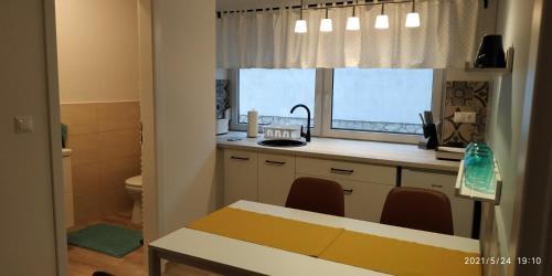 uma cozinha com uma mesa, um lavatório e uma janela em Apartman 3 em Komárom