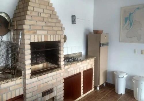a brick fireplace in a kitchen with a refrigerator at MARAVILHOSO SÍTIO NA BEIRA DA REPRESA in Igaratá