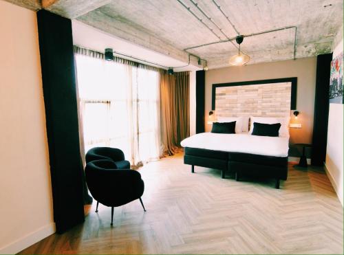 een slaapkamer met een groot bed en een stoel bij Bed, Bites & Business Hotel Rotterdam in Rotterdam