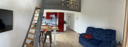 a living room with a staircase and a table and a blue couch at Paille en queue in Saint-Denis