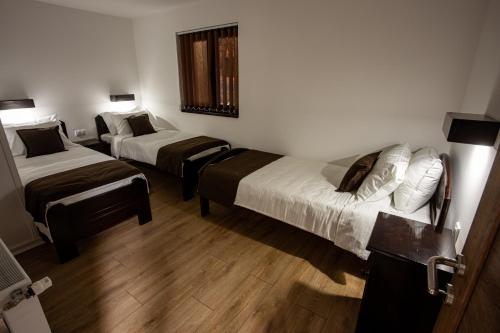 two beds in a hotel room with wooden floors at Vila ZLATARSKA PAHULJA in Nova Varoš