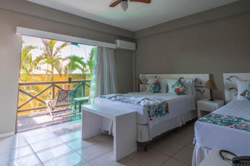 a bedroom with two beds and a balcony at Hotel Pousada Brava Club in Búzios