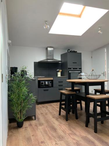 une cuisine avec une table et quelques armoires noires dans l'établissement Vue sur le lac, à Huelgoat