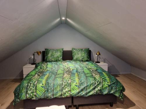 een bed met een groen dekbed op een zolder bij De Rokerij in Monnickendam