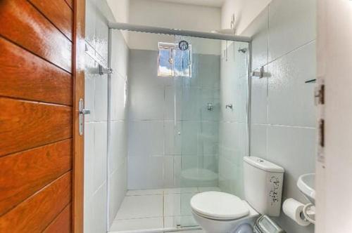 uma casa de banho com um WC e uma cabina de duche em vidro. em Mykonos Residence em São Miguel do Gostoso