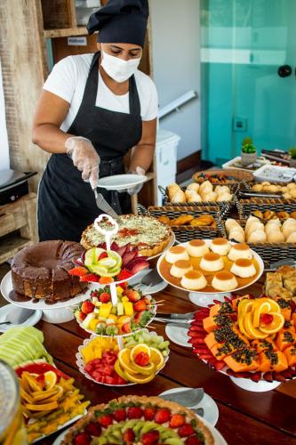 Eine Frau in einer Küche mit einem Tisch voller Essen in der Unterkunft Hotel Pousada Brava Club in Búzios