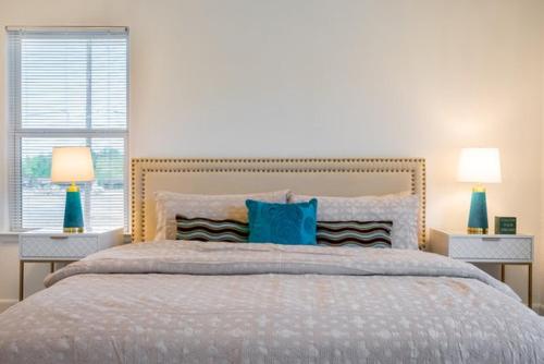 a bedroom with a bed with blue pillows and two lamps at Cute Cozy house close to major sporting events and restaurants in Houston