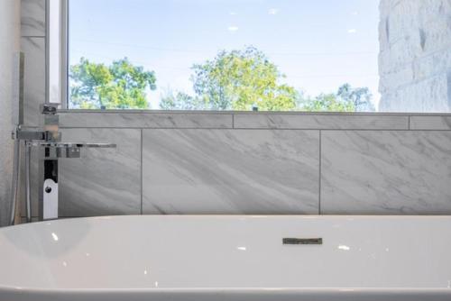 a white bath tub in a bathroom with a window at Cute Cozy house close to major sporting events and restaurants in Houston